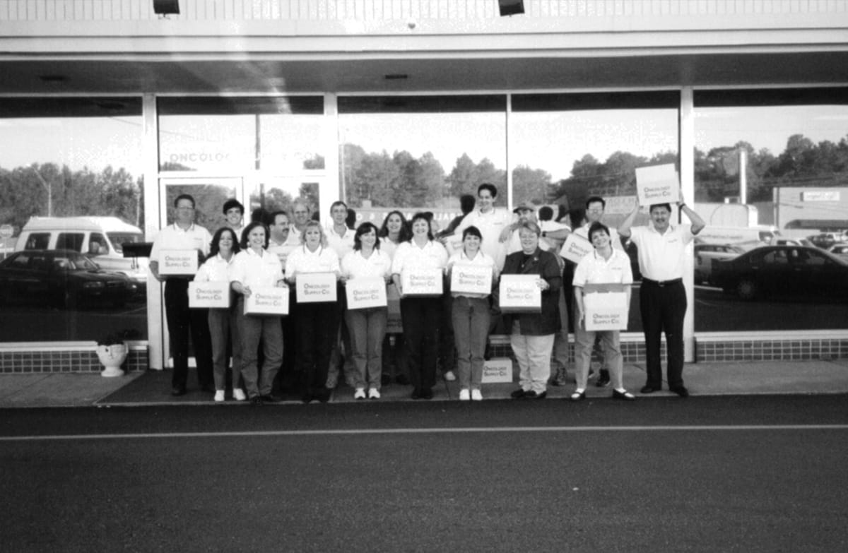 Oncology Supply staff holding boxes in front of office